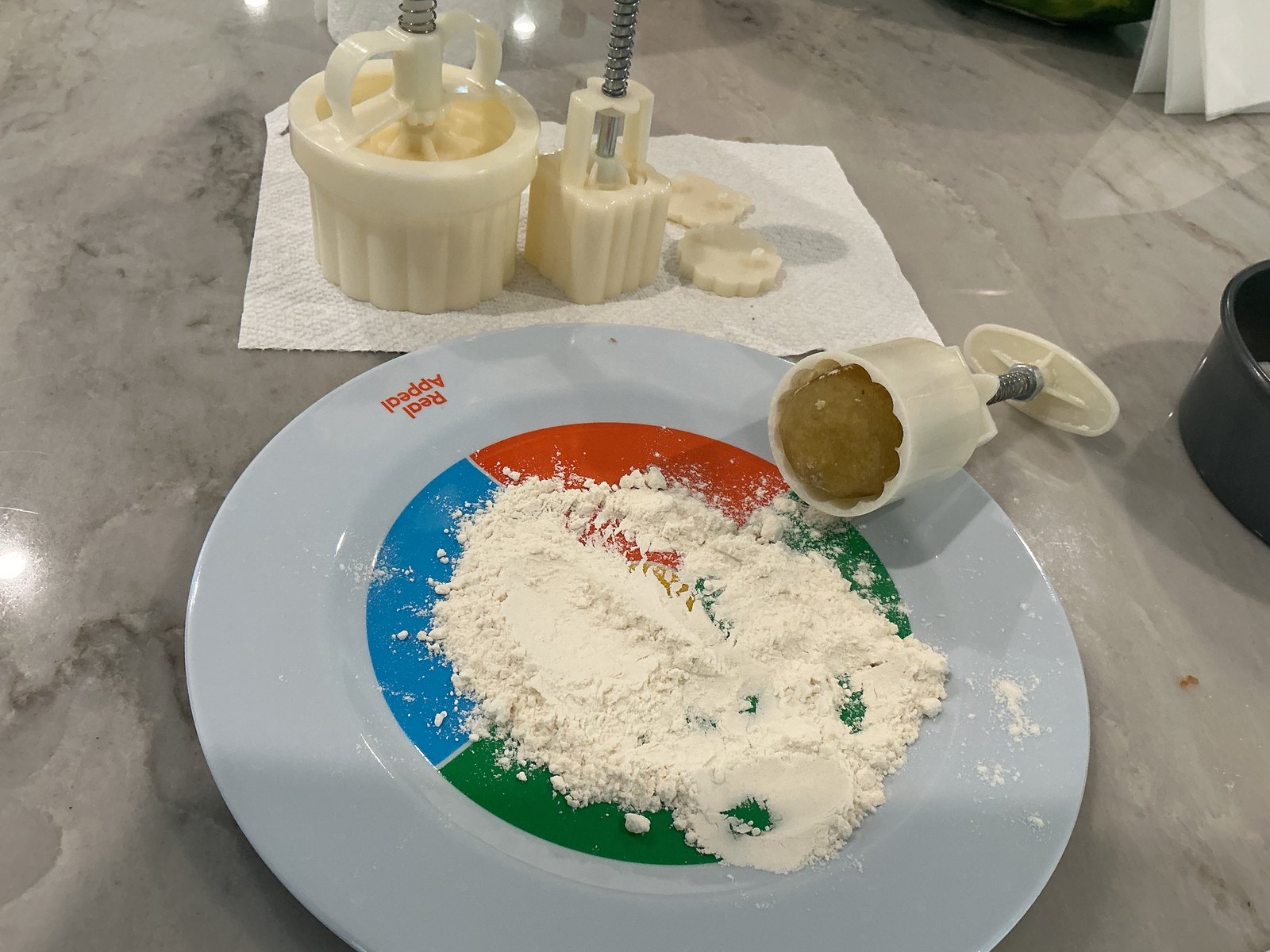 Mooncake presses and patterned inserts beside a plate of dusting flour